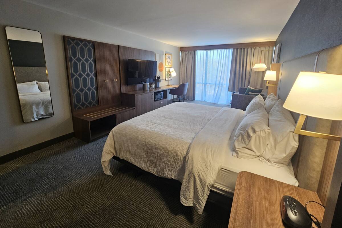 Ein Hotelzimmer mit einem großen Bett, einem Schreibtisch, einem Fernseher und einem Sessel.