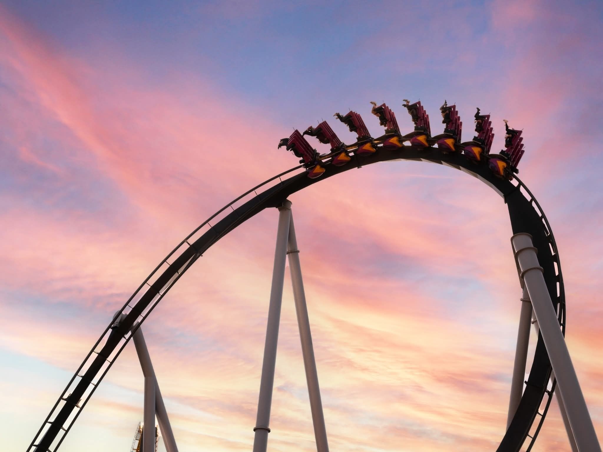 A roller coaster track with a curved structure and a sky with pink and blue hues in the background.