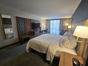 A hotel room with a large bed, a desk, a TV, and a chair. - Holiday Inn Harrisburg - Hershey Area, I-81 by IHG (Grantville)