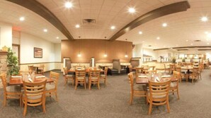 A spacious dining area with multiple tables and chairs, a stone accent wall, and a large American flag. - Holiday Inn Harrisburg - Hershey Area, I-81 by IHG (Grantville)