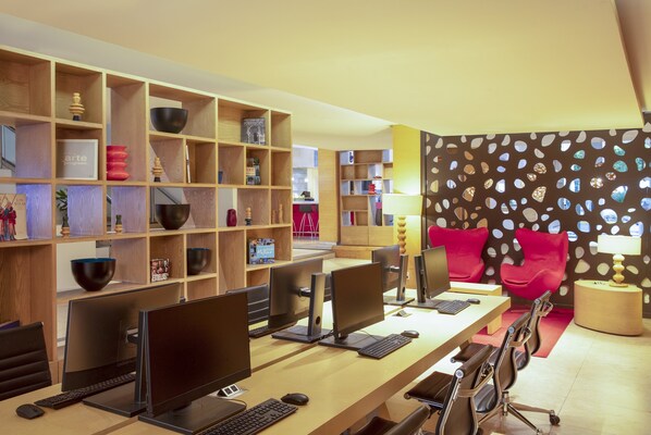 Un espace de travail moderne doté de plusieurs postes informatiques, d’étagères en bois où sont exposés divers objets, et d’un fauteuil rouge qui apporte une touche de couleur.