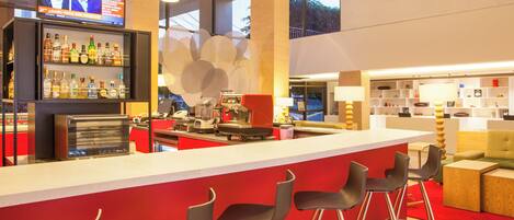 A modern bar area with a long counter, multiple stools, and a television screen displaying news.