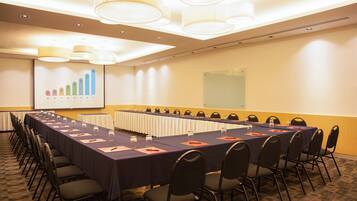 A conference room with a long table, chairs, and a presentation screen.