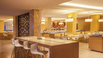 Un moderno vestíbulo de hotel con una zona de bar central, áreas de descanso y una recepción.