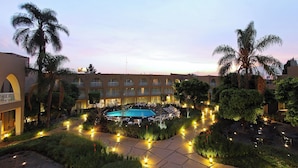 Un patio de hotel con piscina, sillas de descanso y palmeras.