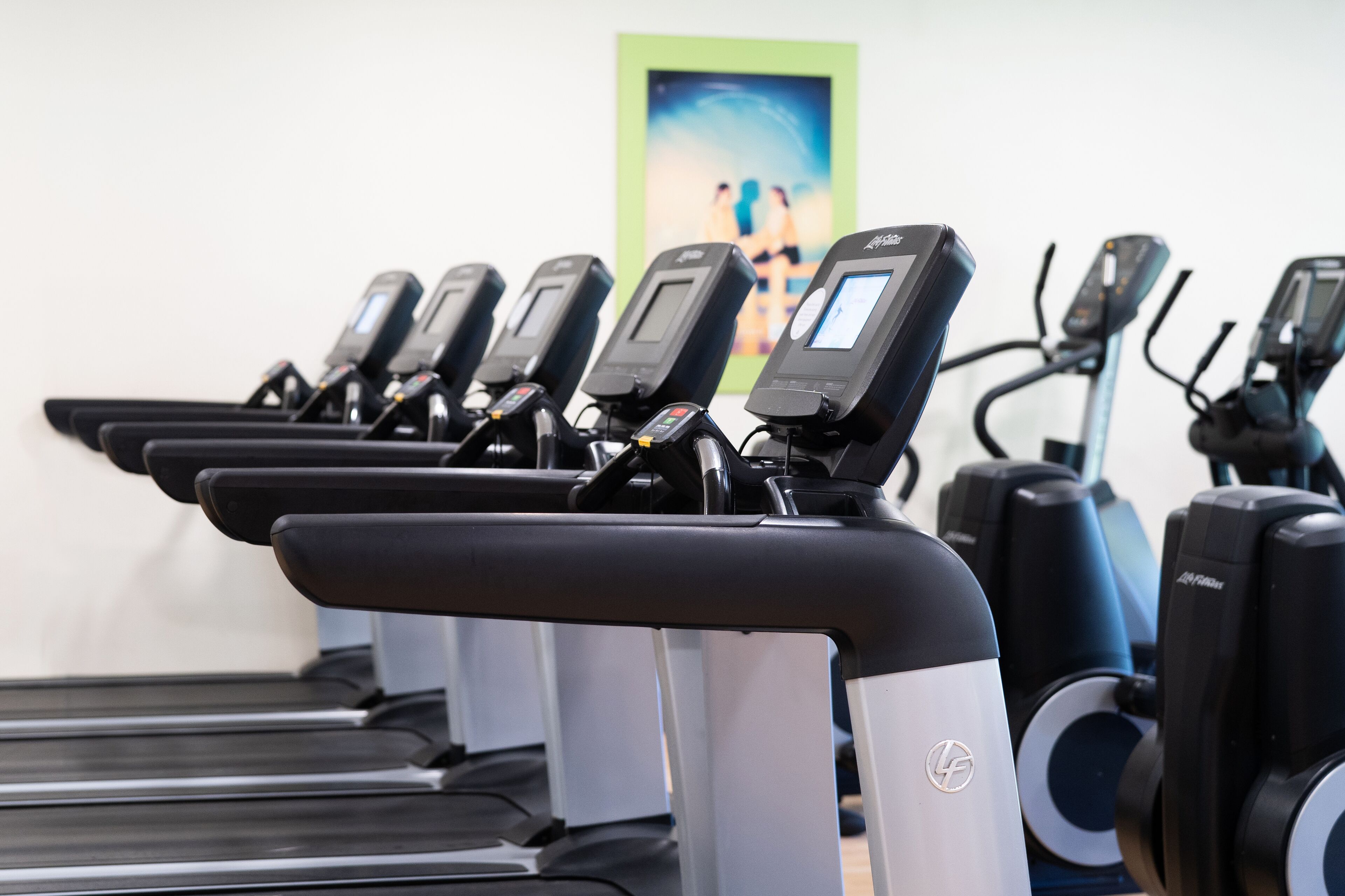 Varias bicicletas estáticas en un gimnasio, con un cartel motivacional al fondo.