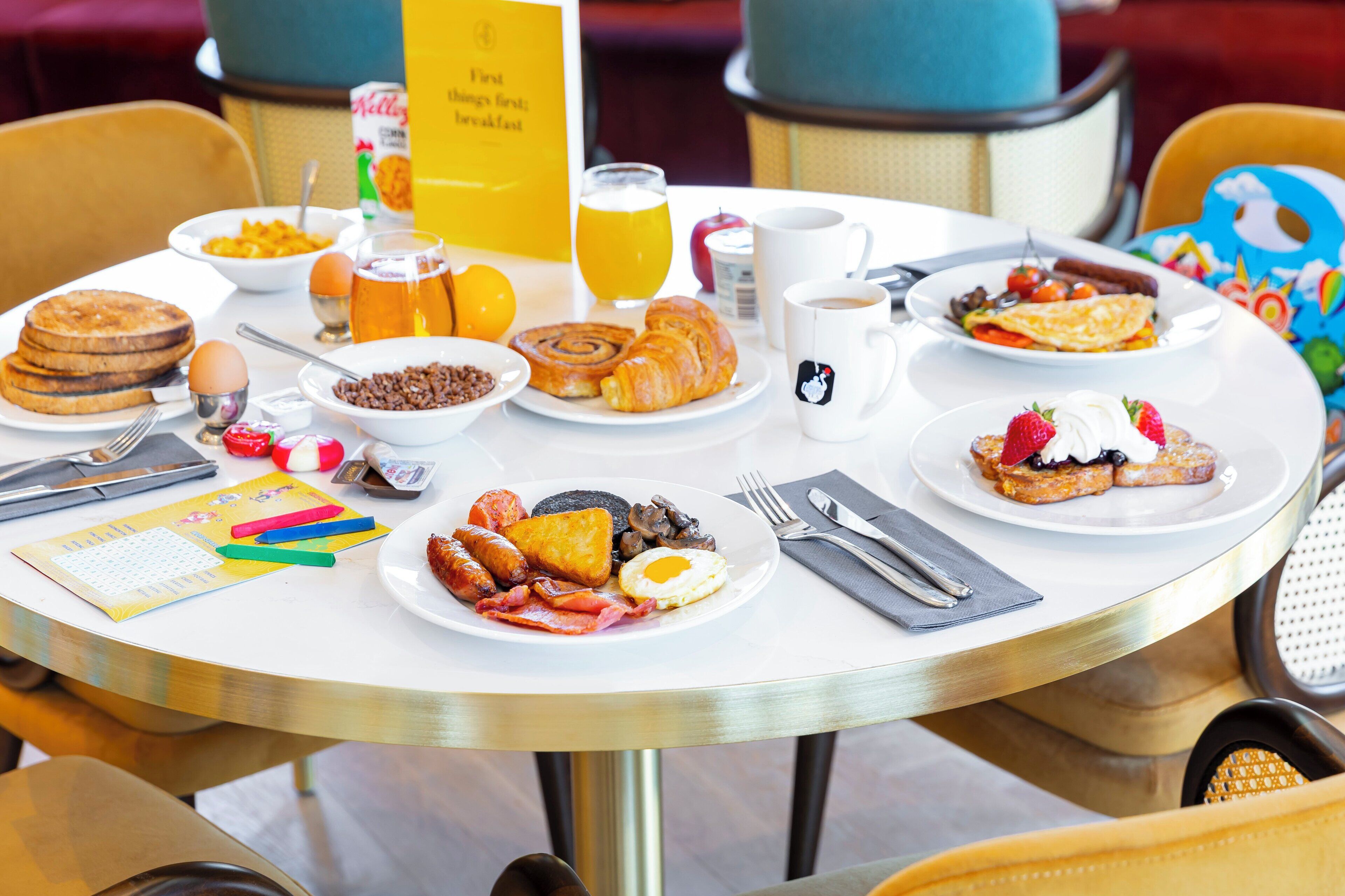 Una mesa de desayuno con diferentes platos, como panqueques, huevos y tostadas.