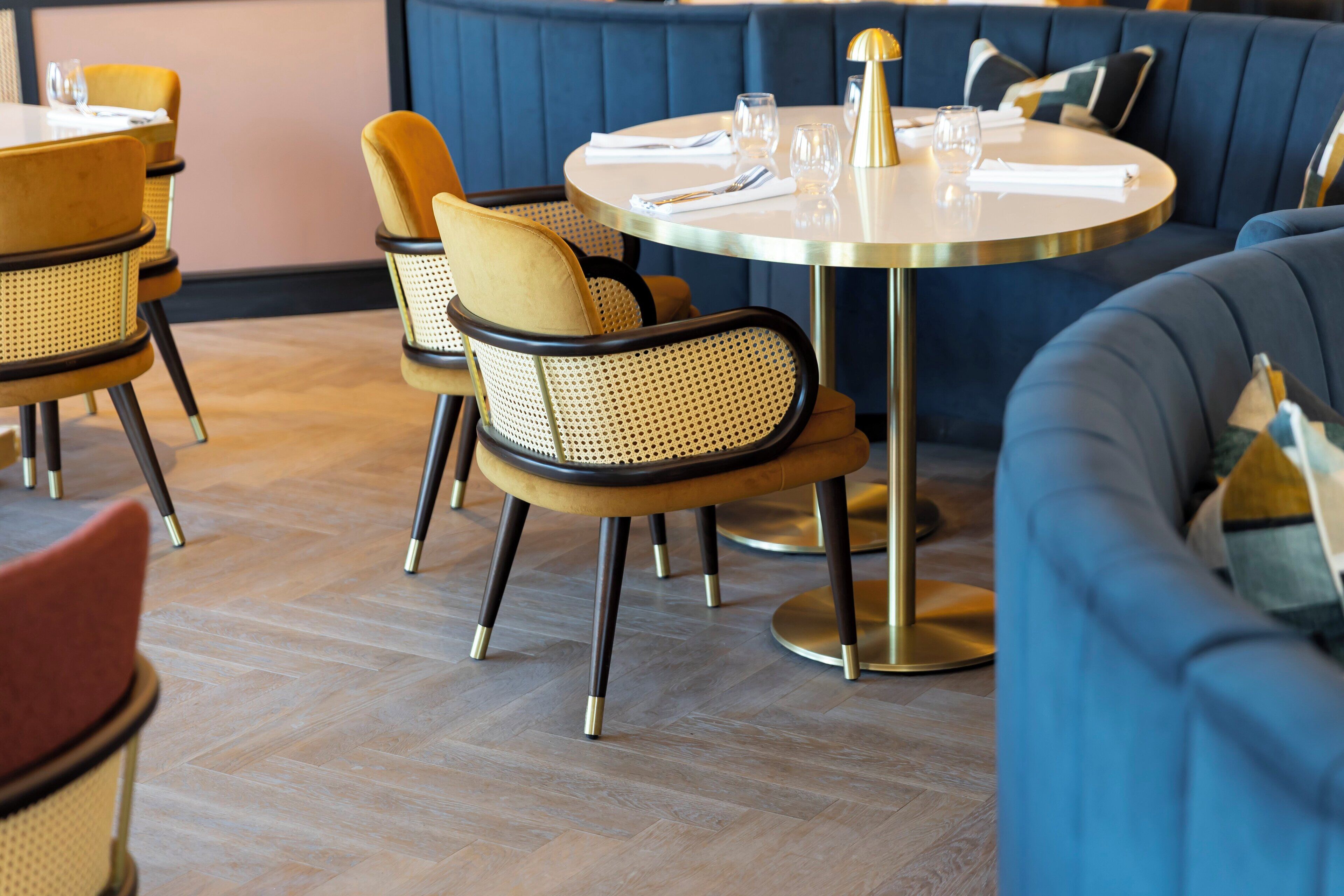 A restaurant interior with round tables, cushioned chairs, and a blue upholstered booth.