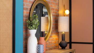 A wooden shelf with a white vase, a terracotta vase, and a blue ceramic mug.