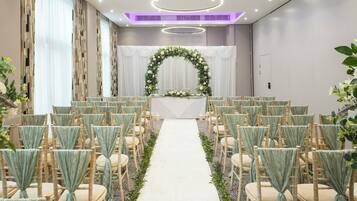 Decoración para una ceremonia de boda, con un arco floral, pasillo y filas de sillas.