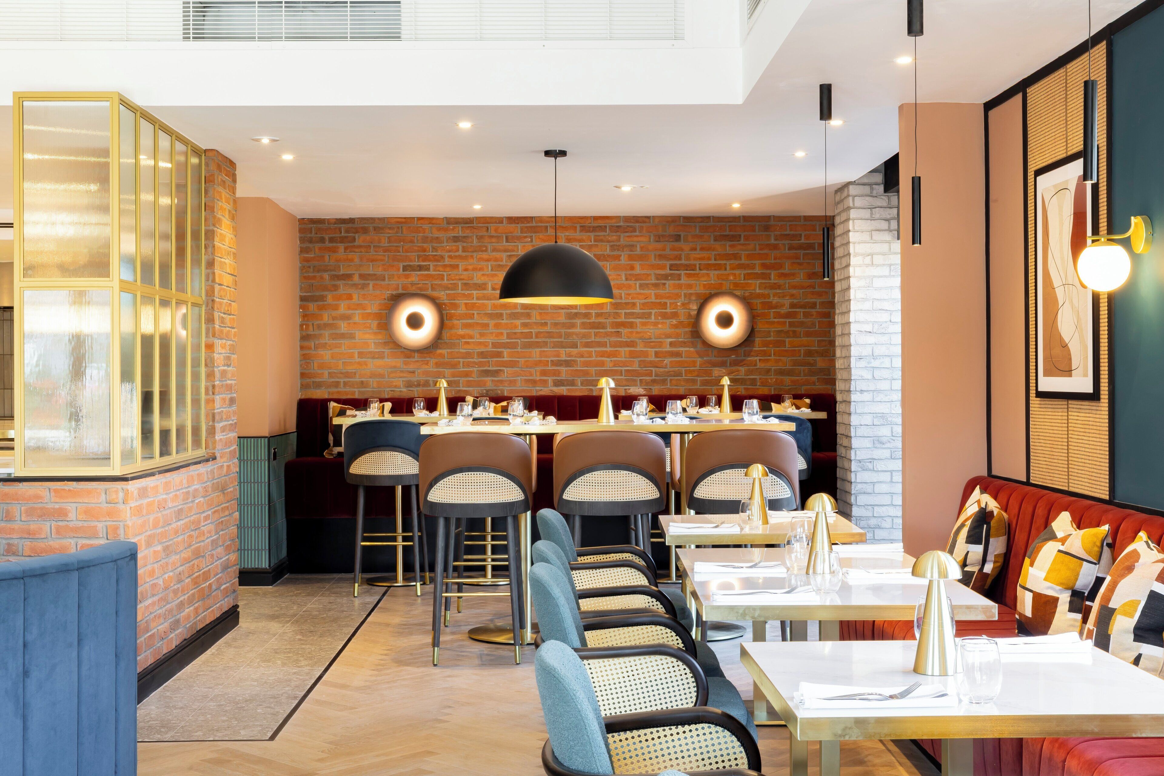 A modern restaurant interior with brick walls, multiple dining tables, and a mix of seating options including booths and chairs.