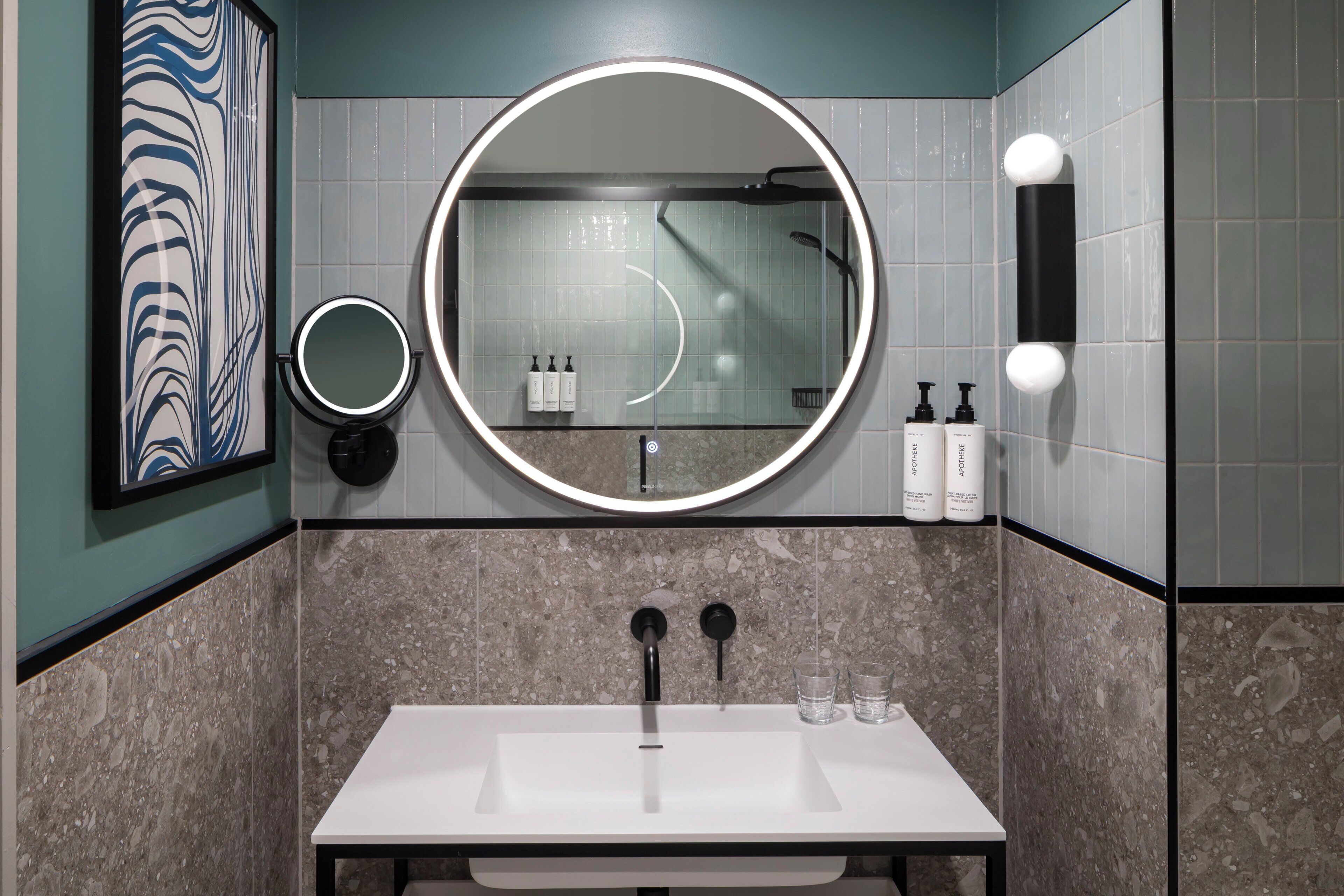 A bathroom with a white sink, two mirrors, a round mirror, and a shower.
