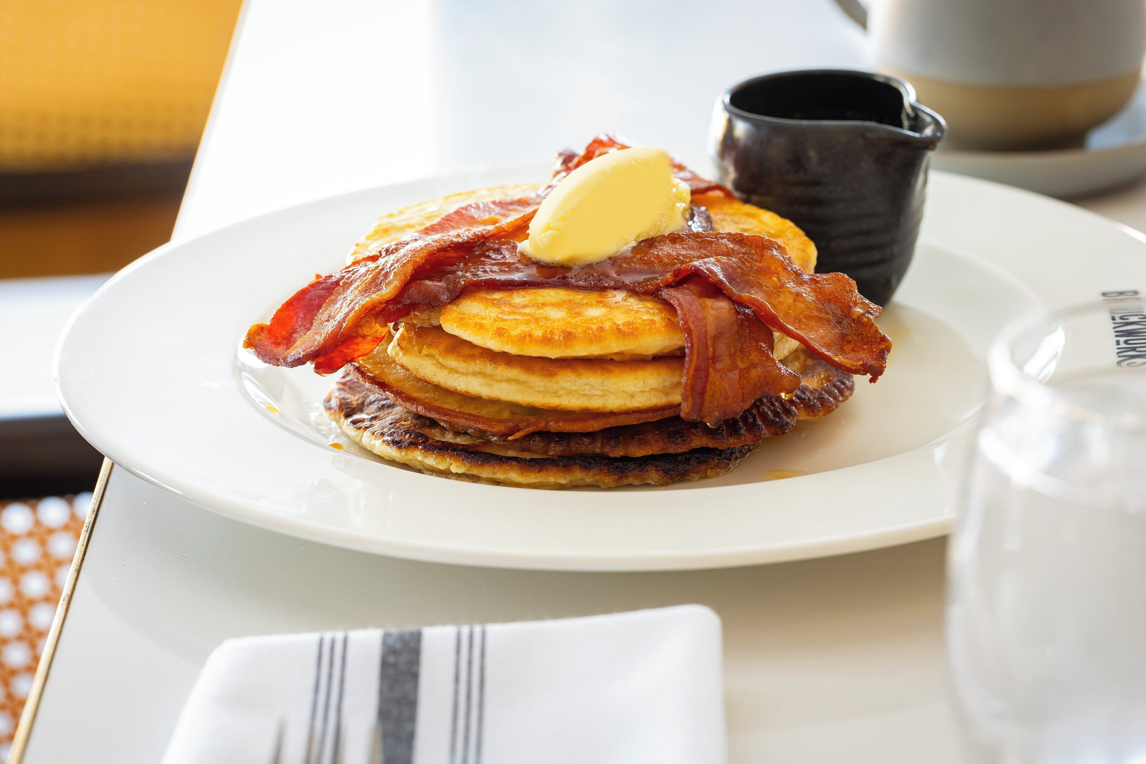 A plate of pancakes with bacon and a pat of butter.