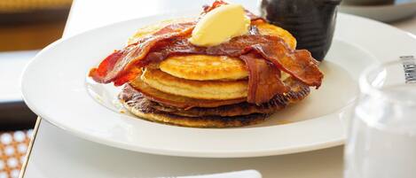 A plate of pancakes with bacon and a pat of butter.