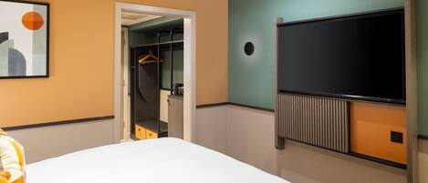 A hotel room with a bed, a wardrobe, a coat rack, and a television.