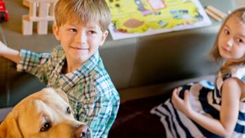 Un niño y un perro en una sala de estar con un juego de mesa y juguetes de madera.