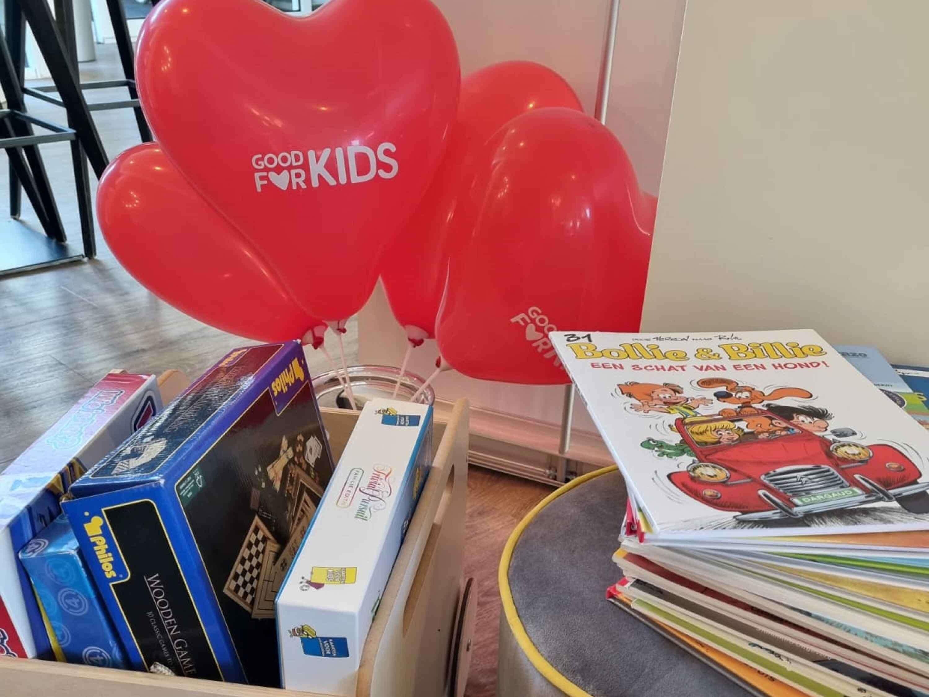 Une exposition de livres et de jouets pour enfants, comprenant un ballon à l’effigie de « Good Kids », des boîtes de jeux en bois et un livre intitulé « Bolle & Billie ».