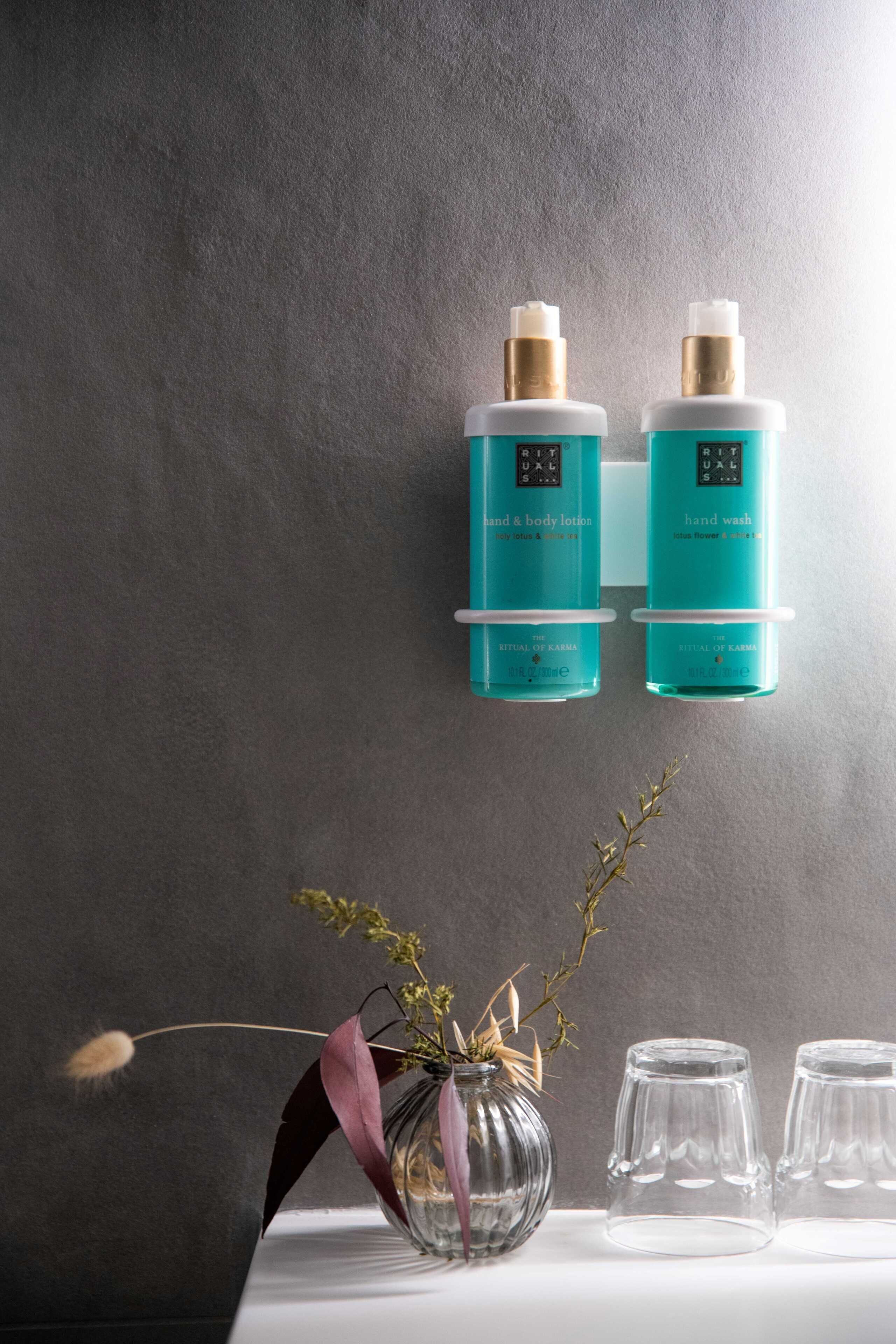 Dos botellas de loción corporal y lavamanos sobre una pared.