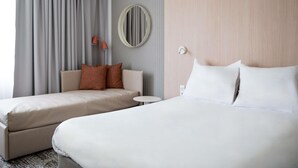 Una habitación de hotel con dos camas, una mesita, una lámpara y una lámpara de pared.