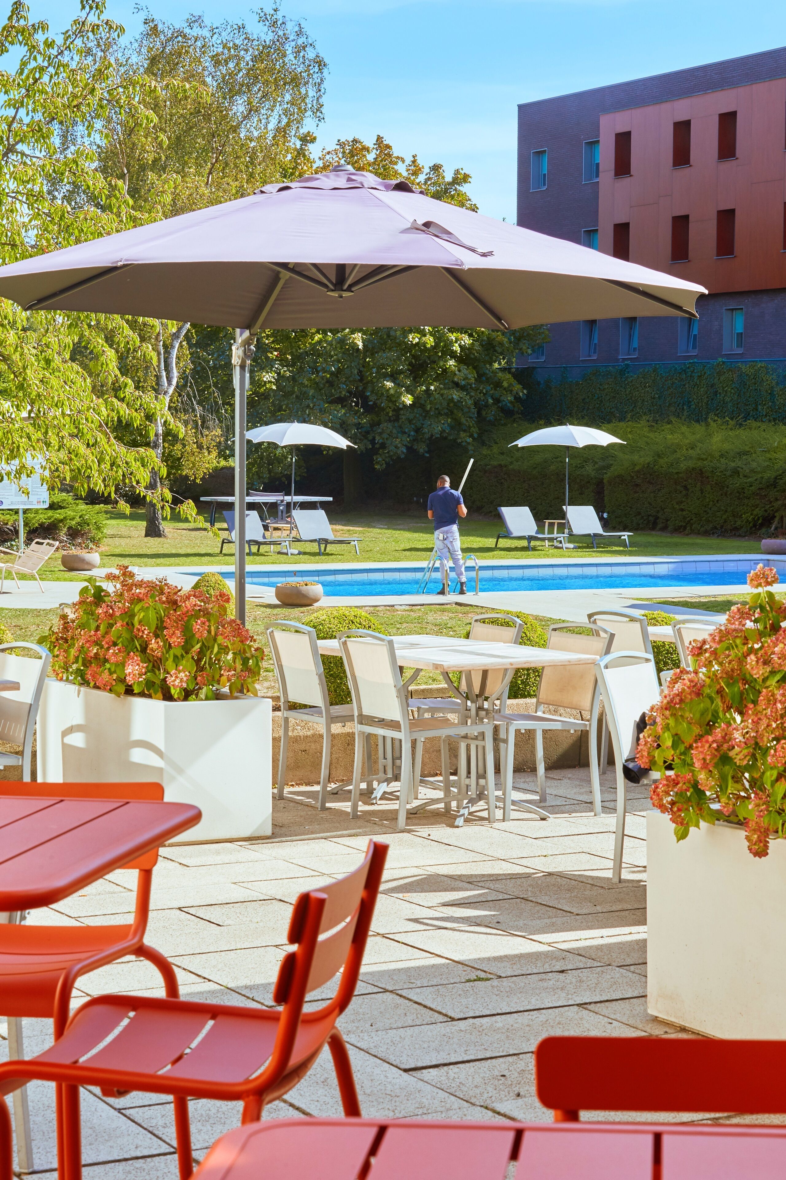 An outdoor pool area with lounge chairs, umbrellas, and potted plants.