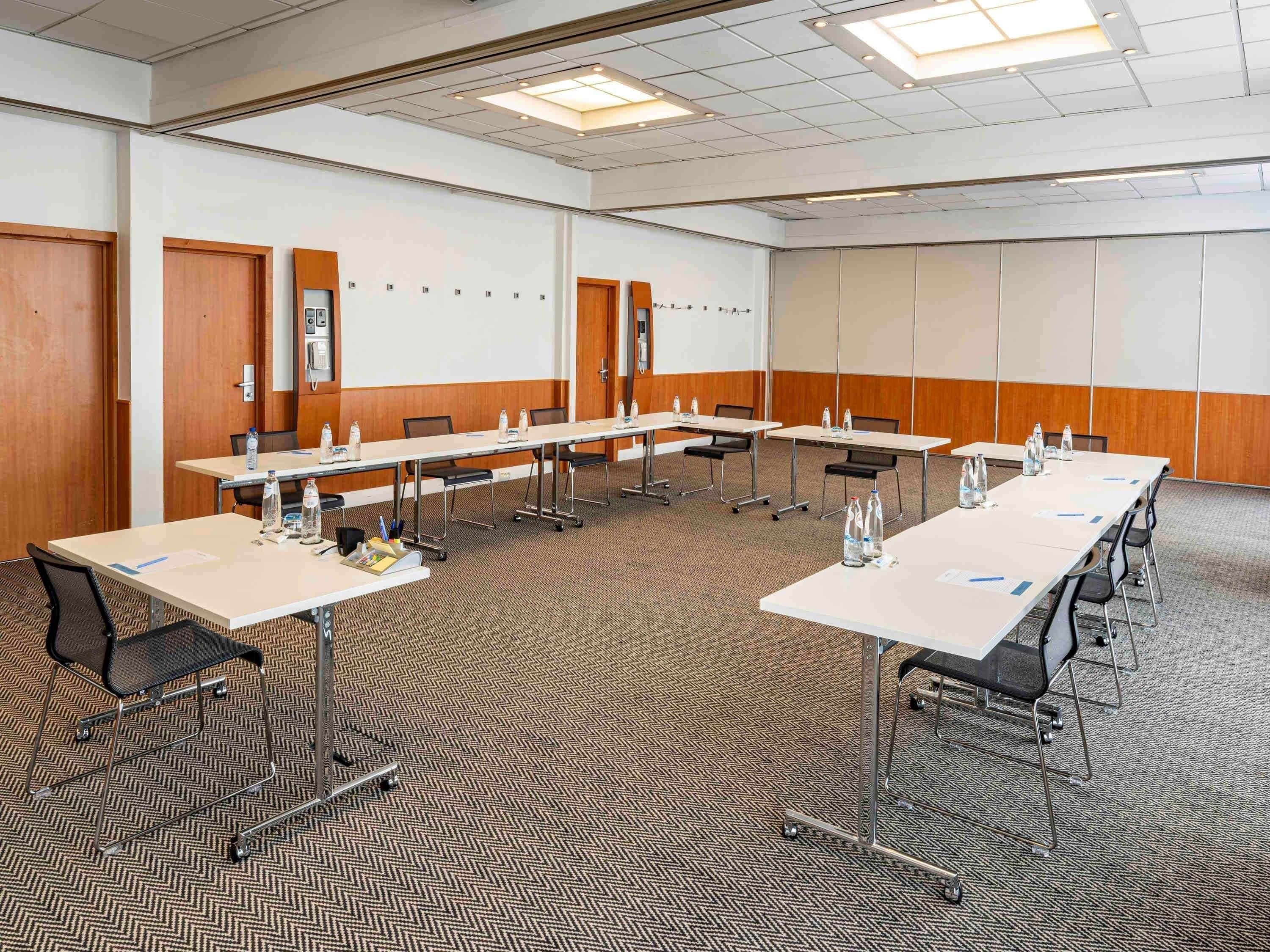 A conference room with multiple tables, chairs, and a carpeted floor.