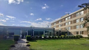 Un edificio moderno con entrada de vidrio, un camino pavimentado y un césped cuidado.