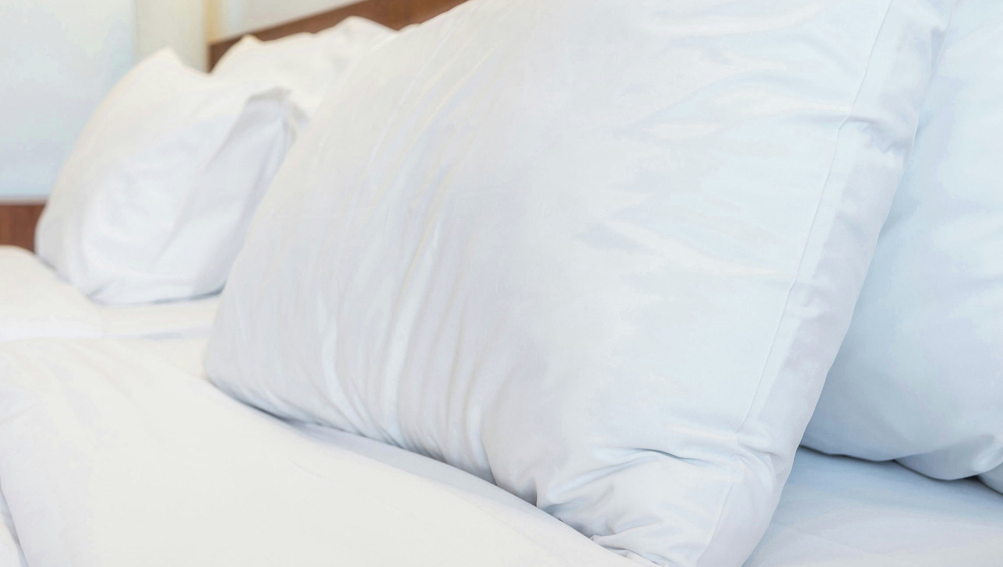 A bed with white bedding and pillows.