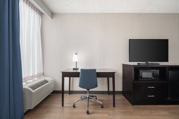 Una habitación de hotel con escritorio, silla, televisión y calefacción.
