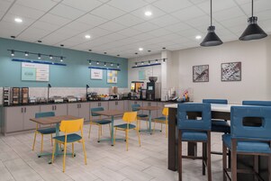 A modern cafe with a counter, seating area, and artwork on the walls.