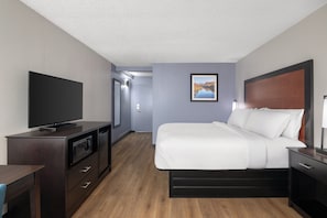 A hotel room with a bed, a TV, a desk, and a microwave.