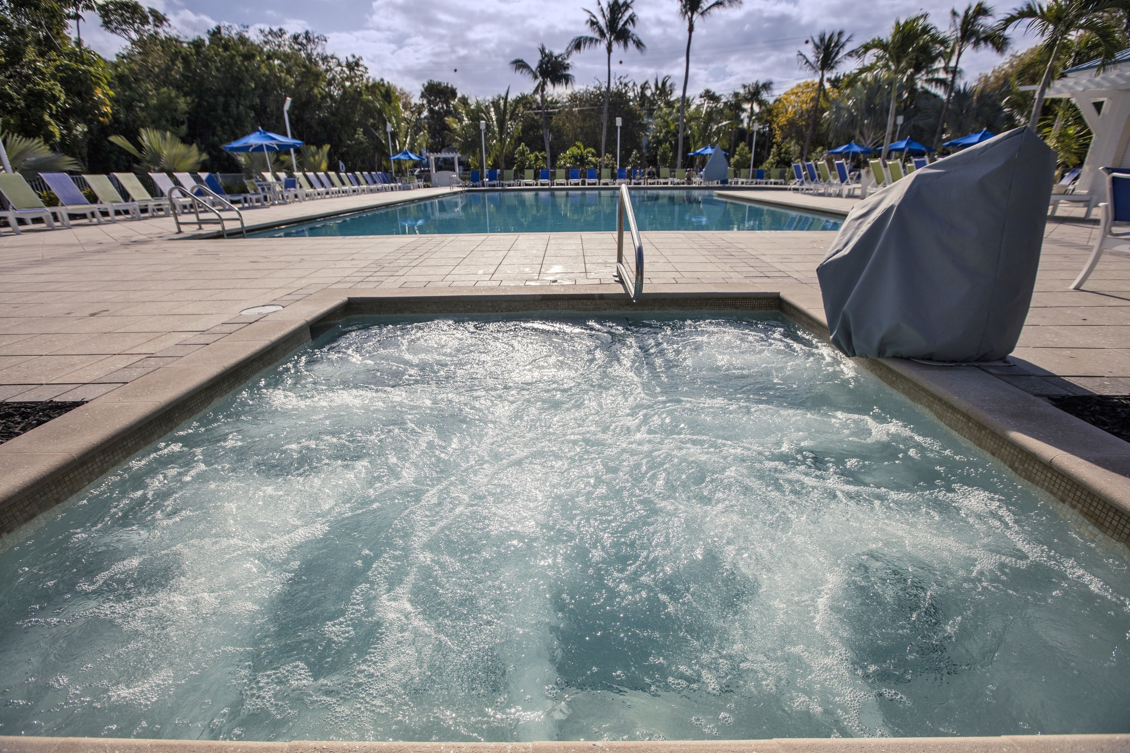 A swimming pool with a water feature, surrounded by lounge chairs and umbrellas.