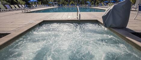 A swimming pool with a water feature, surrounded by lounge chairs and umbrellas.