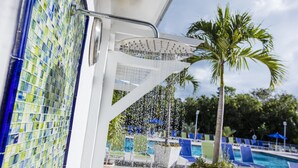 Ein Poolbereich mit Wasserspiel, einer Palme und Liegestühlen.
