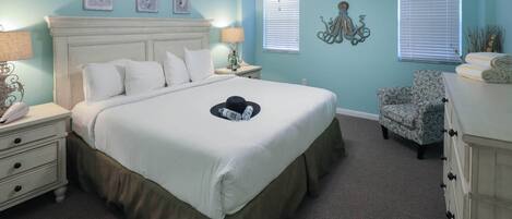 A bedroom with a large bed, a ceiling fan, and a chair.