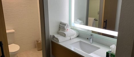 A modern bathroom with a white sink, a large mirror, and a toilet.