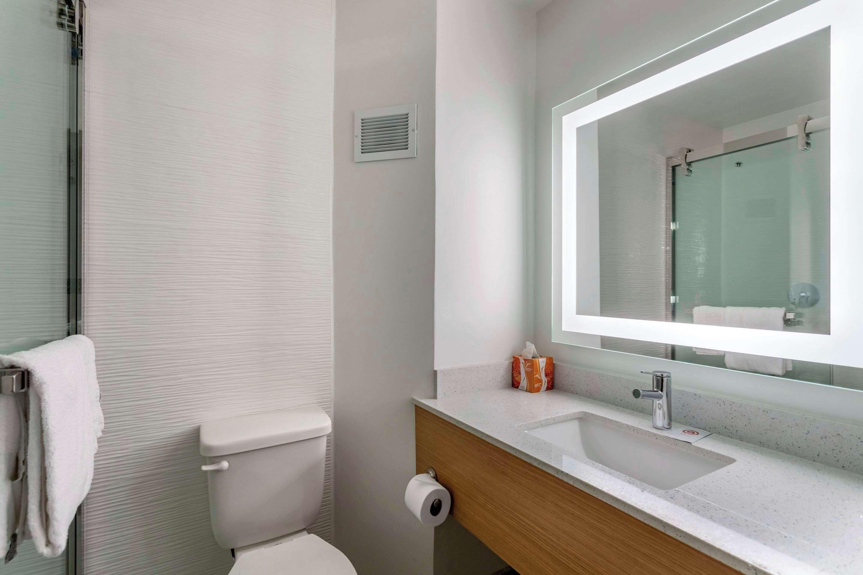 Un baño moderno con inodoro, lavamanos y espejo.