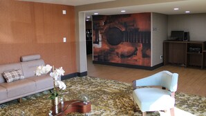 Un hall con un sofá, una silla, una mesita de centro y un jarrón decorativo.