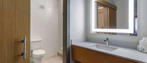A modern bathroom with a wooden vanity, a large mirror, and a toilet.
