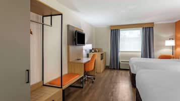 Una habitación de hotel con una cama, un escritorio con silla, televisor, ventana con cortinas y una lámpara de noche.