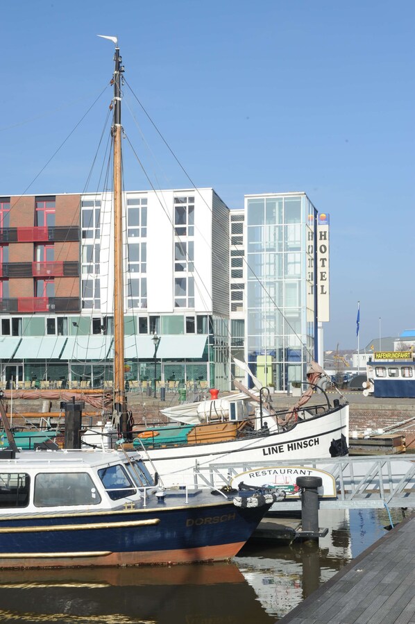 A docked boat with 'LINE HINSCH' and 'RESTAURANT' signage, a building with 'HOTEL' signage, and a clear blue sky. - Nordsee Hotel Bremerhaven Fischereihafen (Bremerhaven)