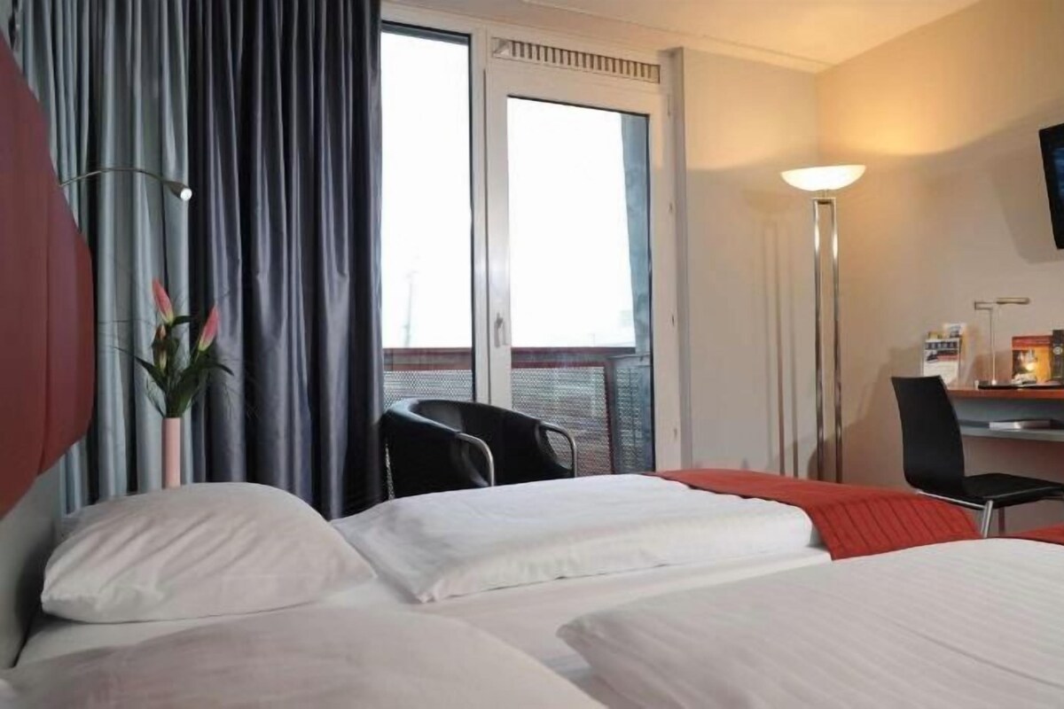 Een hotelkamer met een bed, een bureau, een stoel, een televisie en een raam.