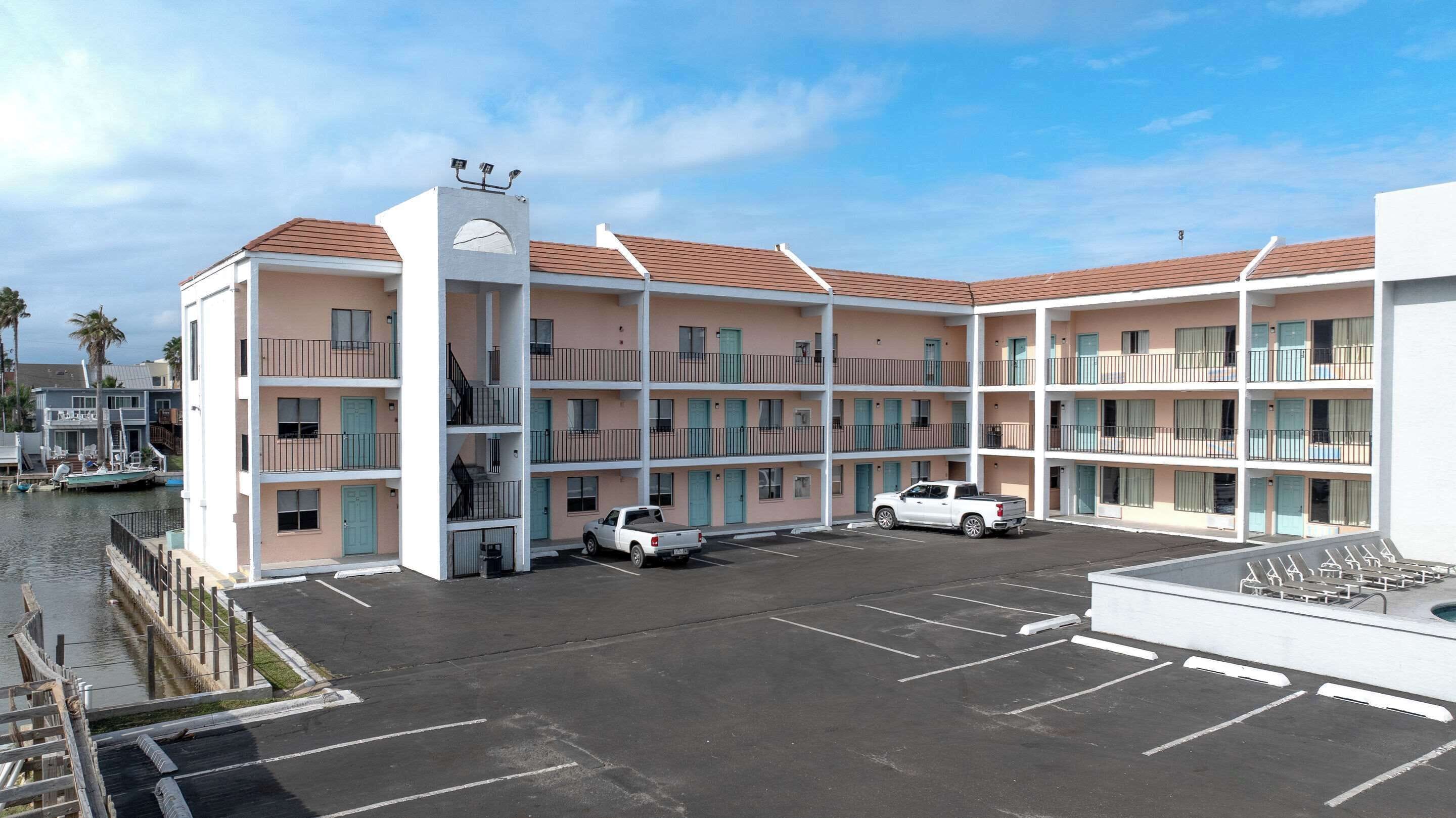 A multi-story motel with a parking lot and a dock area.