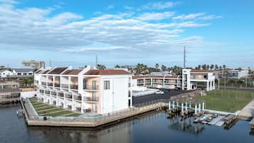 A waterfront hotel with multiple balconies, a pool area, and a parking lot.