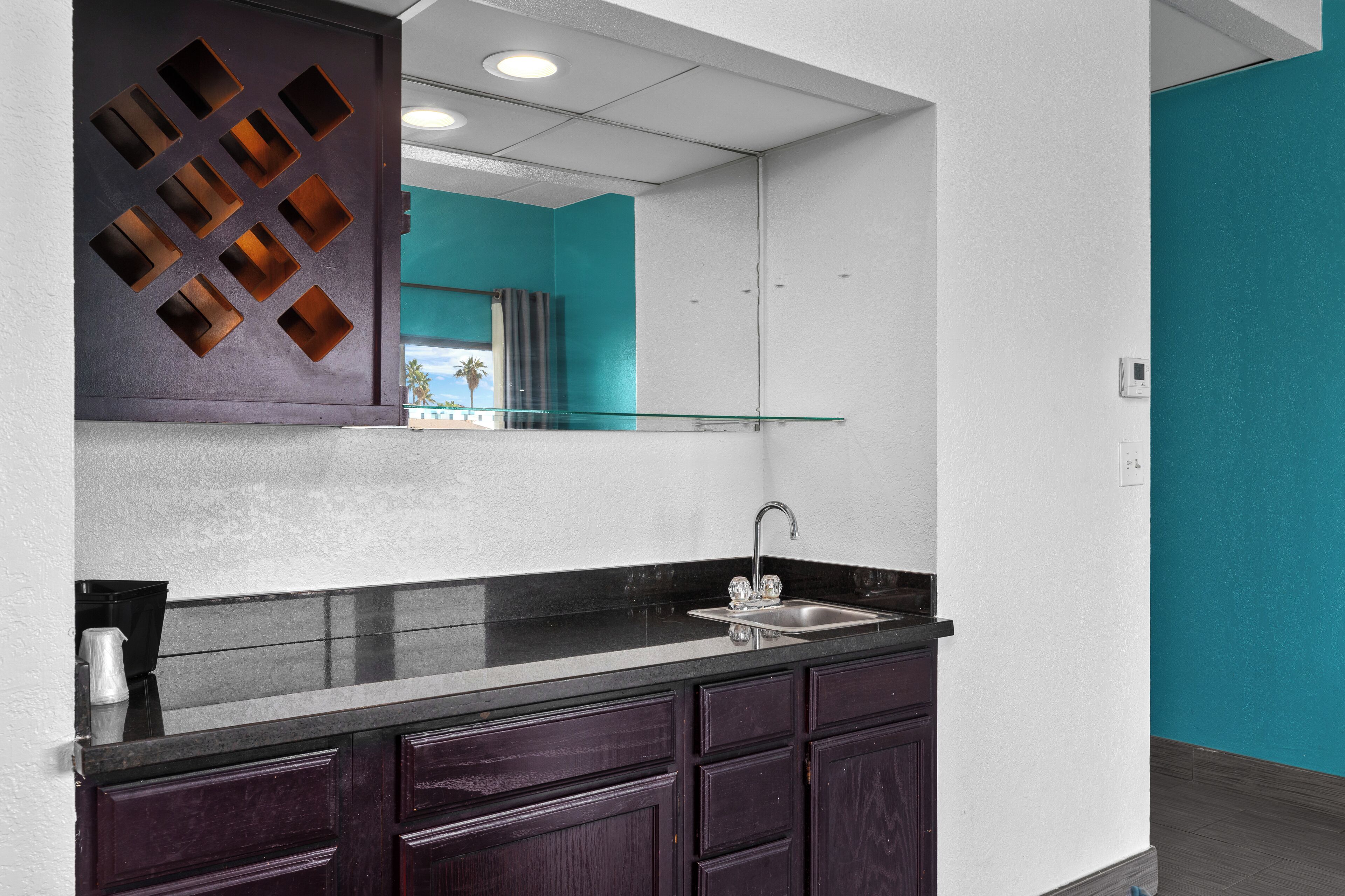 A modern kitchen with dark cabinets, a black countertop, and a stainless steel sink.