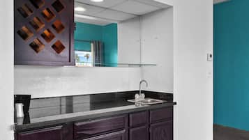 A modern kitchen with dark cabinets, a black countertop, and a stainless steel sink.