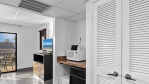 Cocina compacta con microondas, un refrigerador pequeño y una encimera con vistas al exterior.