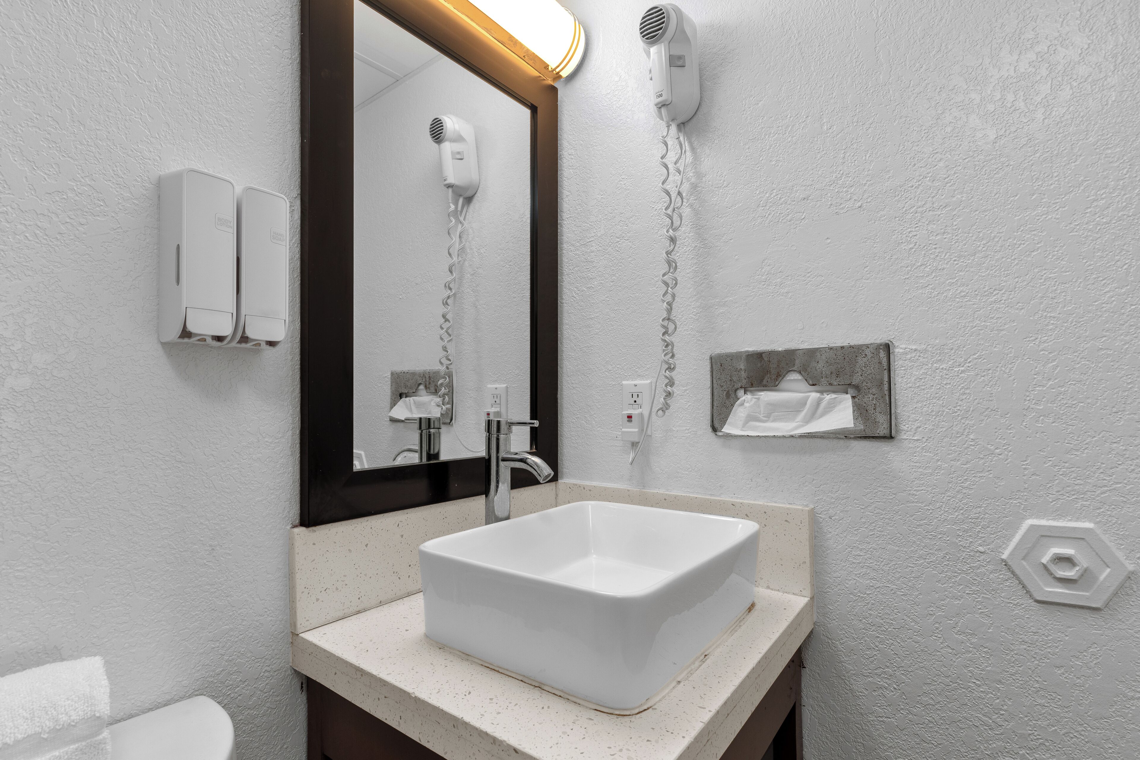 A bathroom with a white sink, a mirror, a hairdryer, and a towel rack.