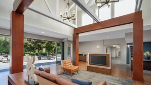 A spacious living area with a wooden coffee table, leather sofa, and a TV.