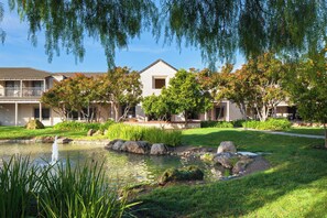 A residential area with a pond, well-maintained lawns, and a building with a balcony. - Four Points by Sheraton Pleasanton (Pleasanton)