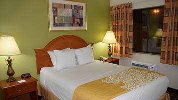 A hotel room with a bed, two bedside tables with lamps, a framed artwork on the wall, and a window with curtains.